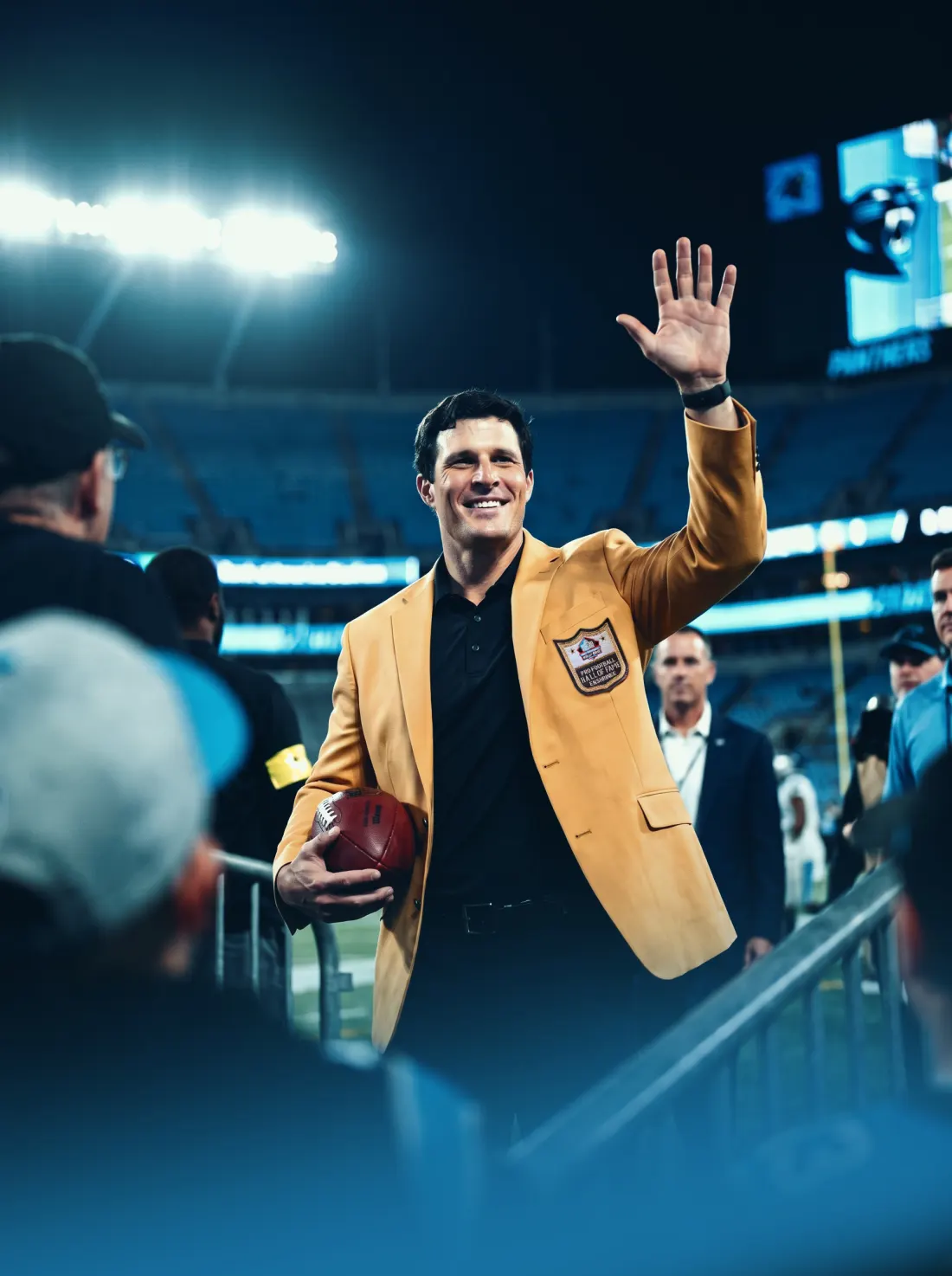 Luke Kuechly waving to the crowd in his Hall of Fame jacket