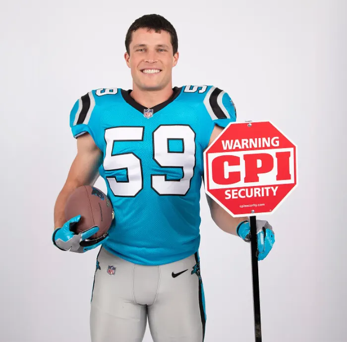 Luke Kuechly in a Panthers jersey holding a CPI sign